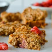 A strawberry oatmeal bar wtih more bars in the background.