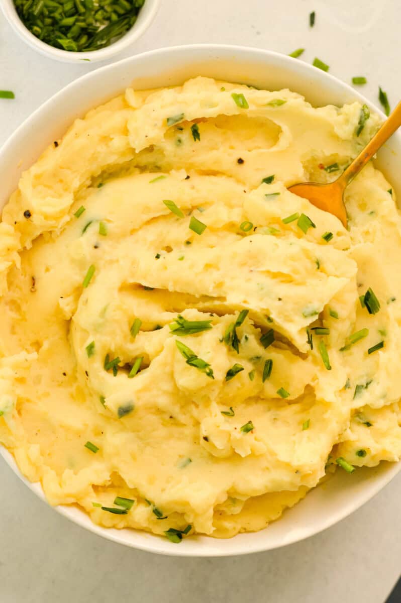 Birds eye of bowl of yukon gold mashed potatoes topped with chives.