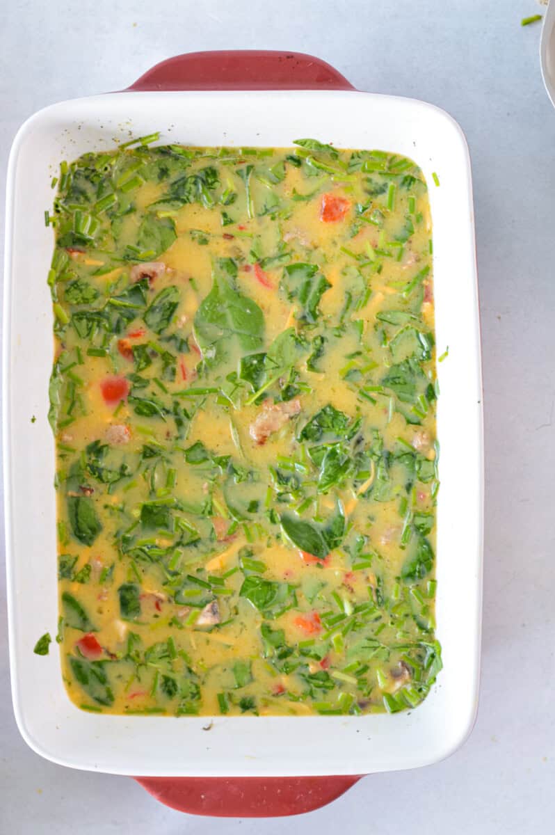 Casserole dish with whisked eggs, veggies and sausage.