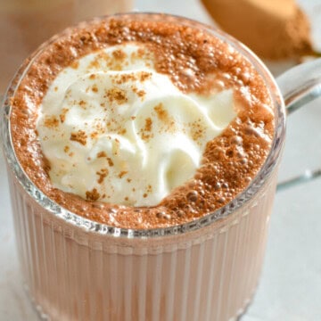 Mug of high protein hot chocolate, topped with whipped cream.