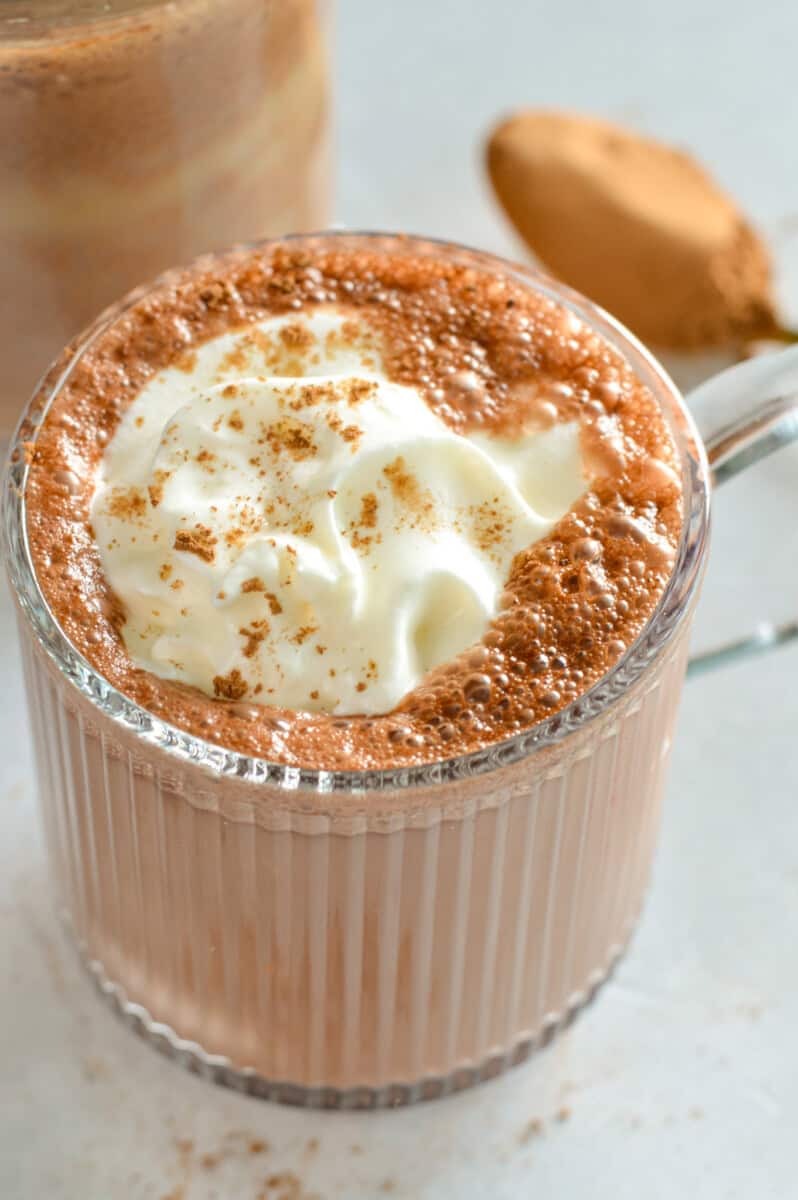 Mug of high protein hot chocolate, topped with whipped cream.