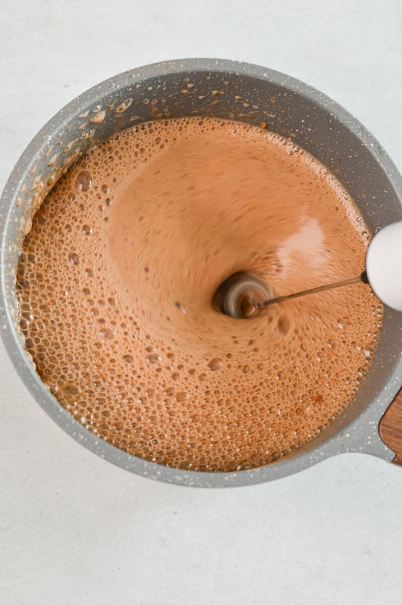 Whisking protein hot chocolate with an electric whisk.