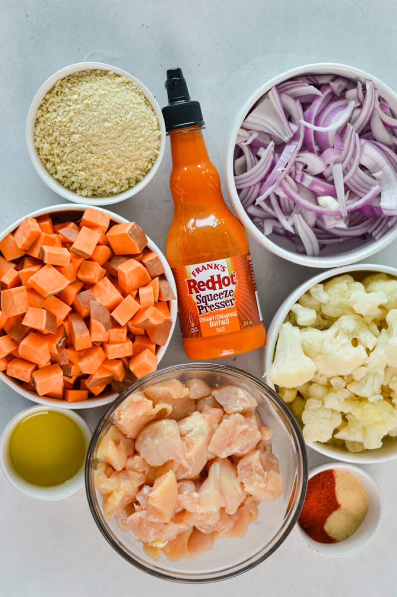 Ingredients including buffalo sauce, sweet potato, red onion, chicken, cauliflower, seasoning, panko and olive oil.