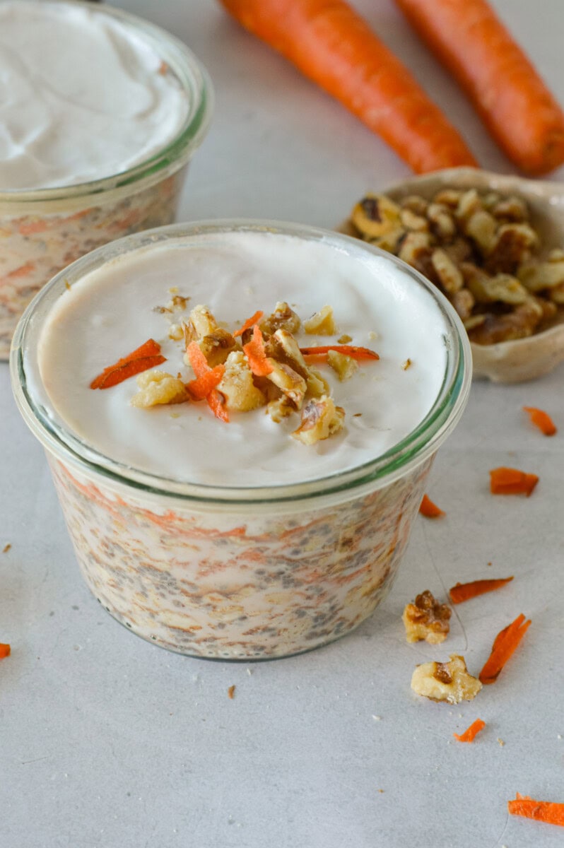 Jar of carrot cake overnight oats topped with walntus and shredded carrots.