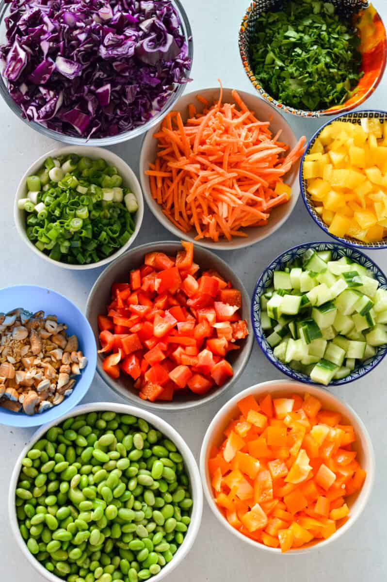 Ingredients including carrots, peppers, cucumber, edamame, cilantro, cashew, red cabbage, and green onion.