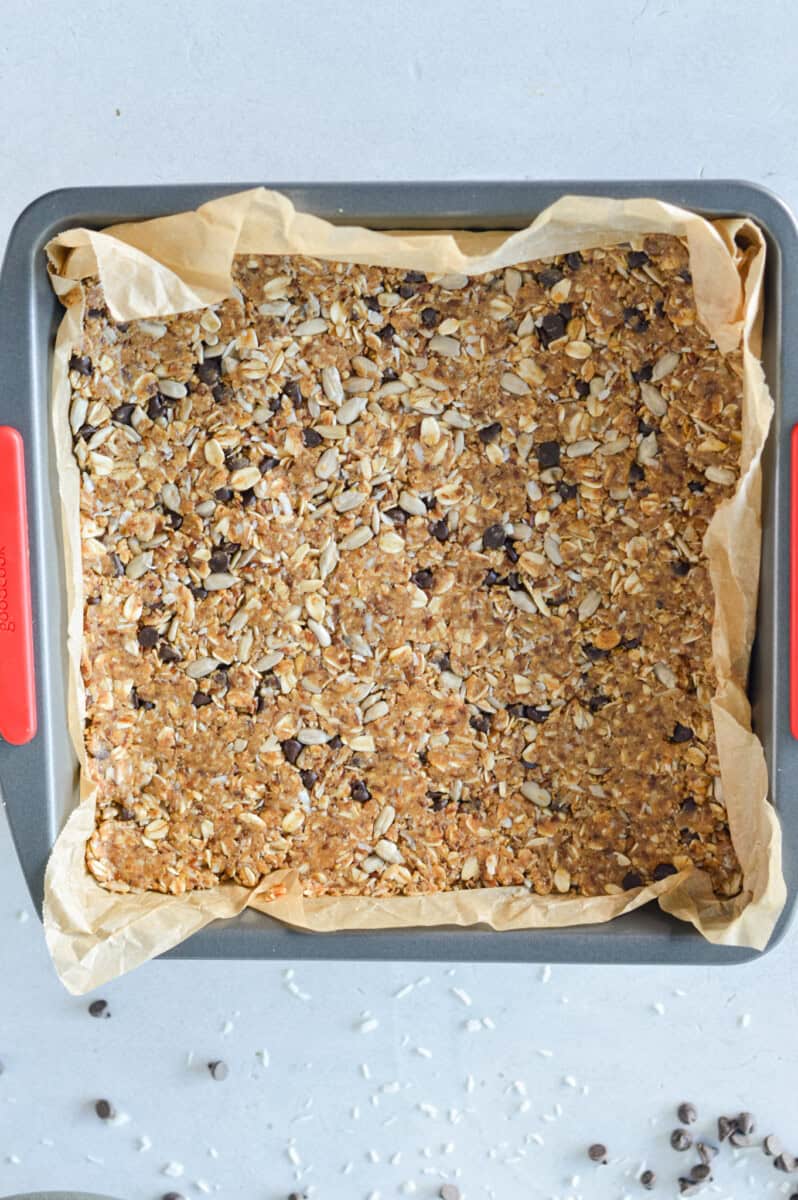 Pressing granola bar mixture into a lined pan.