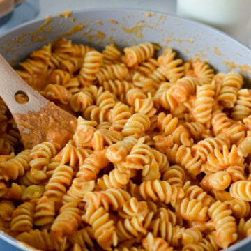 Mixing a pan of pasta wiht roasted tomato pasta sauce.