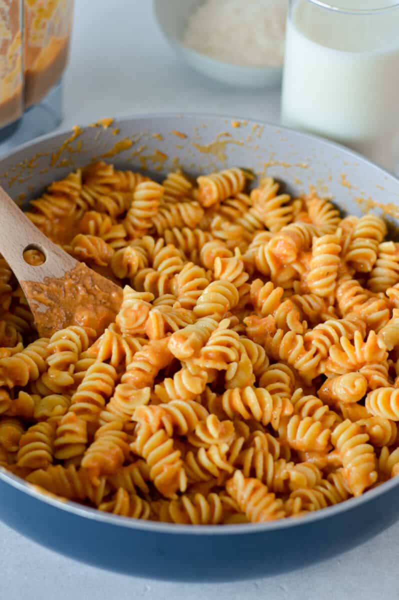 Mixing a pan of pasta wiht roasted tomato pasta sauce.