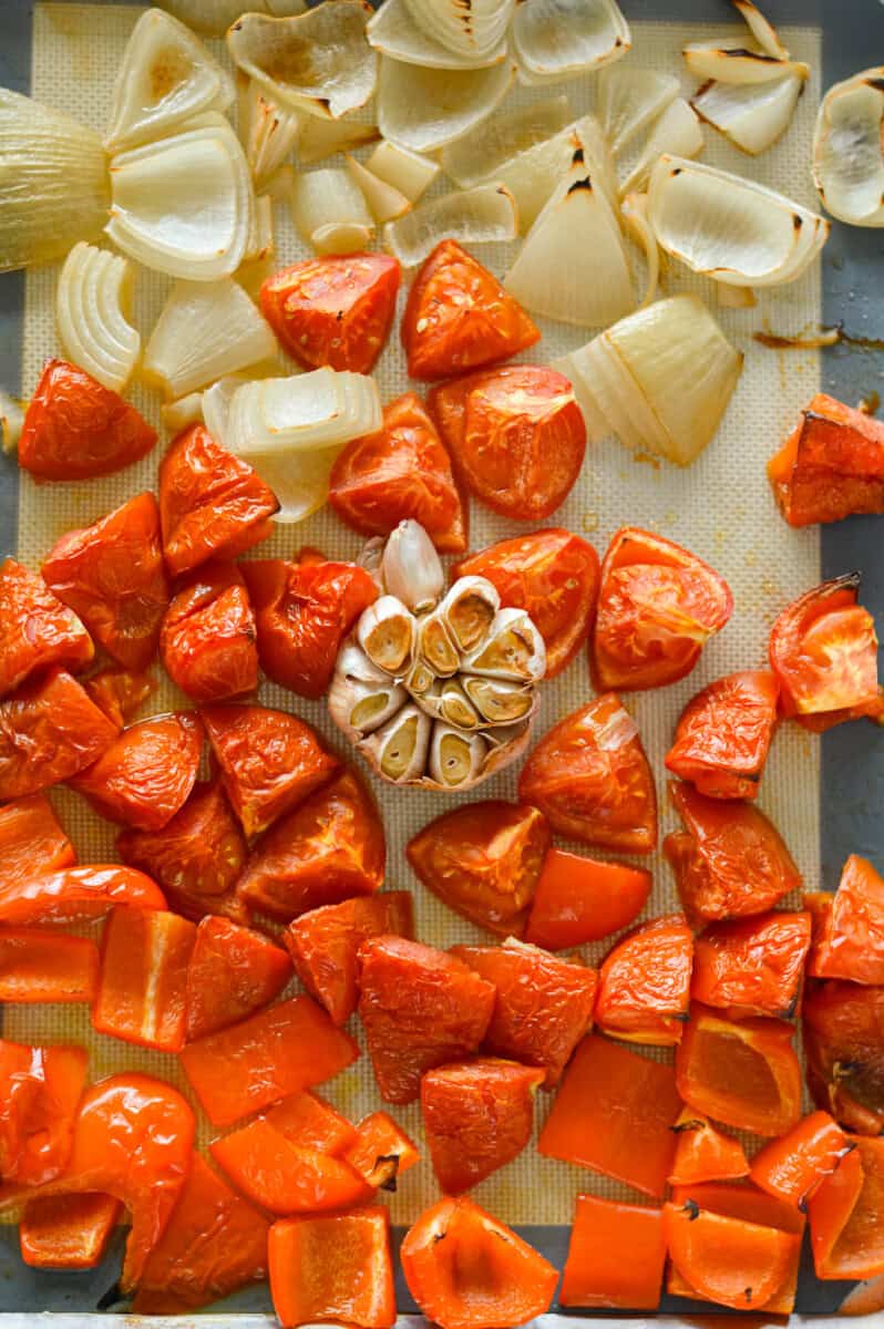Sheet pan with roasted tomato, bell pepper, onion, and garlic.