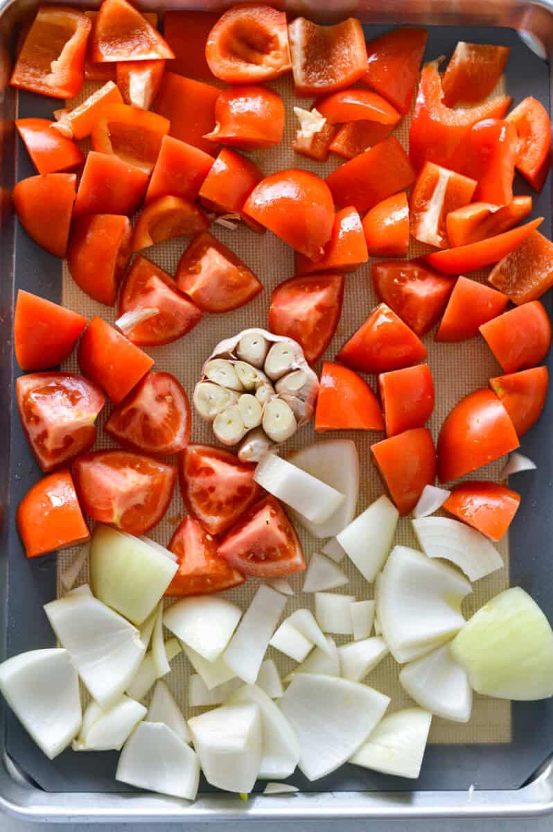 Sheet pan with chopped tomatoes, bell pepper, onions and garlic.