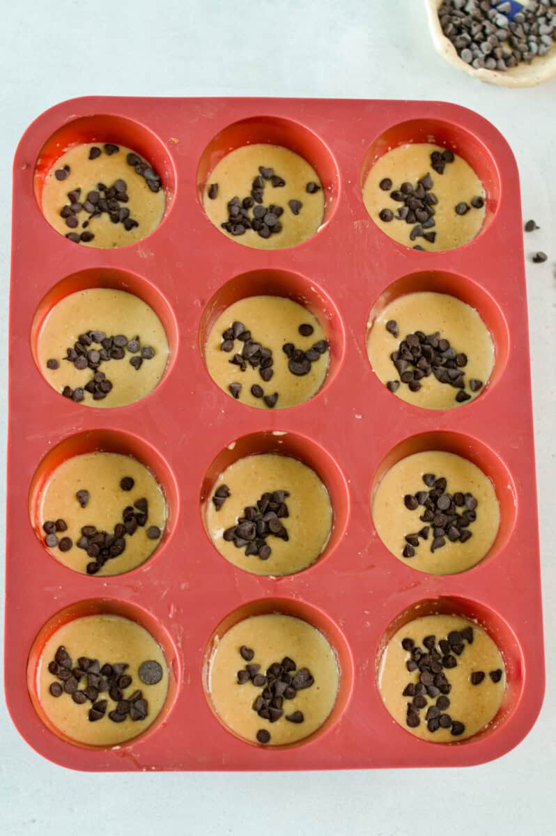 A red muffin tray with protein banana muffin batter.