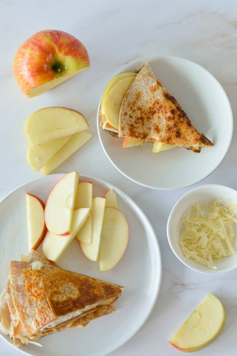 Birds eye of plates with turkey apple cheddar quesadilla served with leftover apple slices.