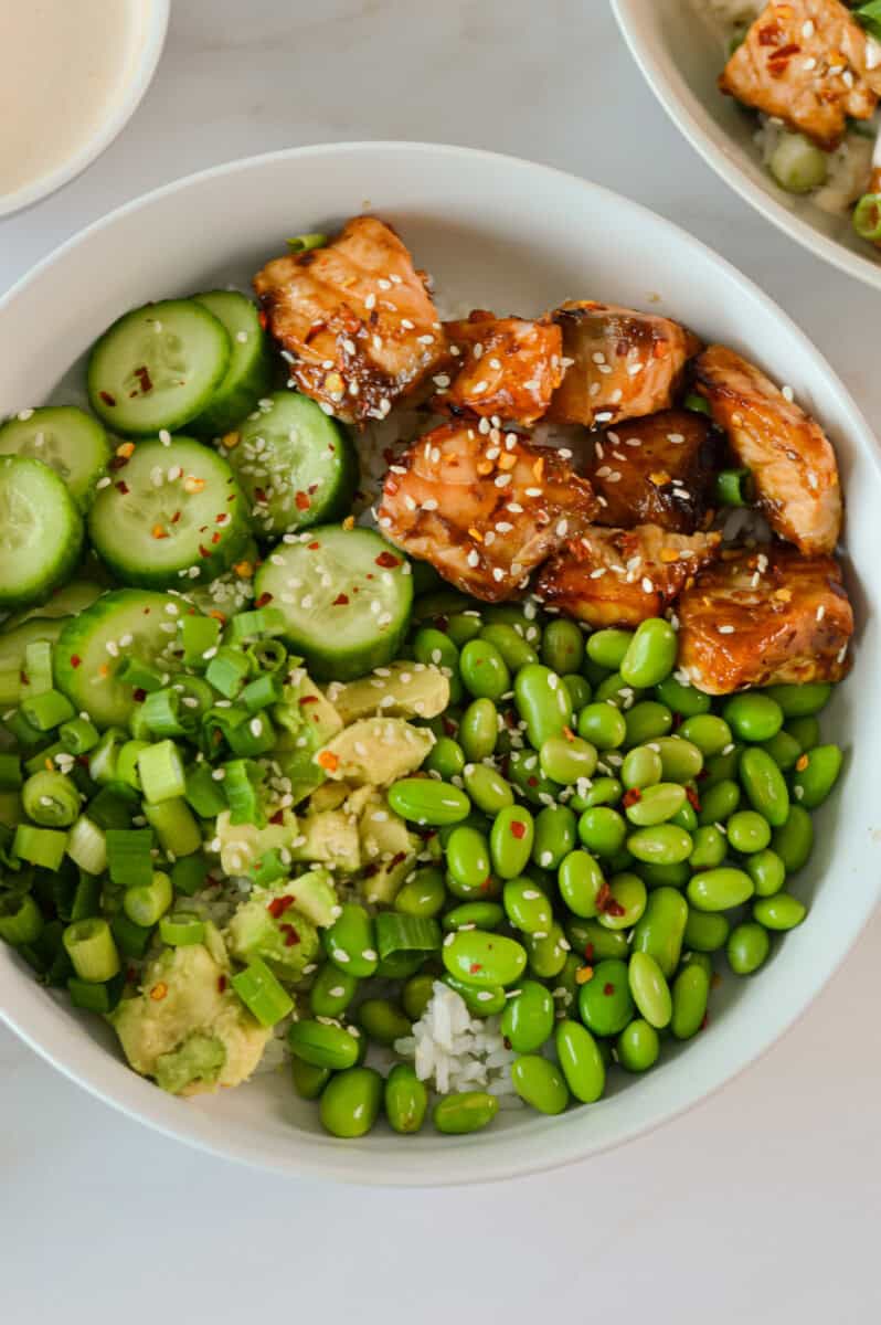 Birds eye of unmixed salmon bowl with rice, cucumber, edamame and avocado.