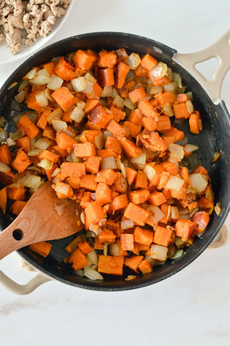 Cooking sweet potato and onion in a skillet.