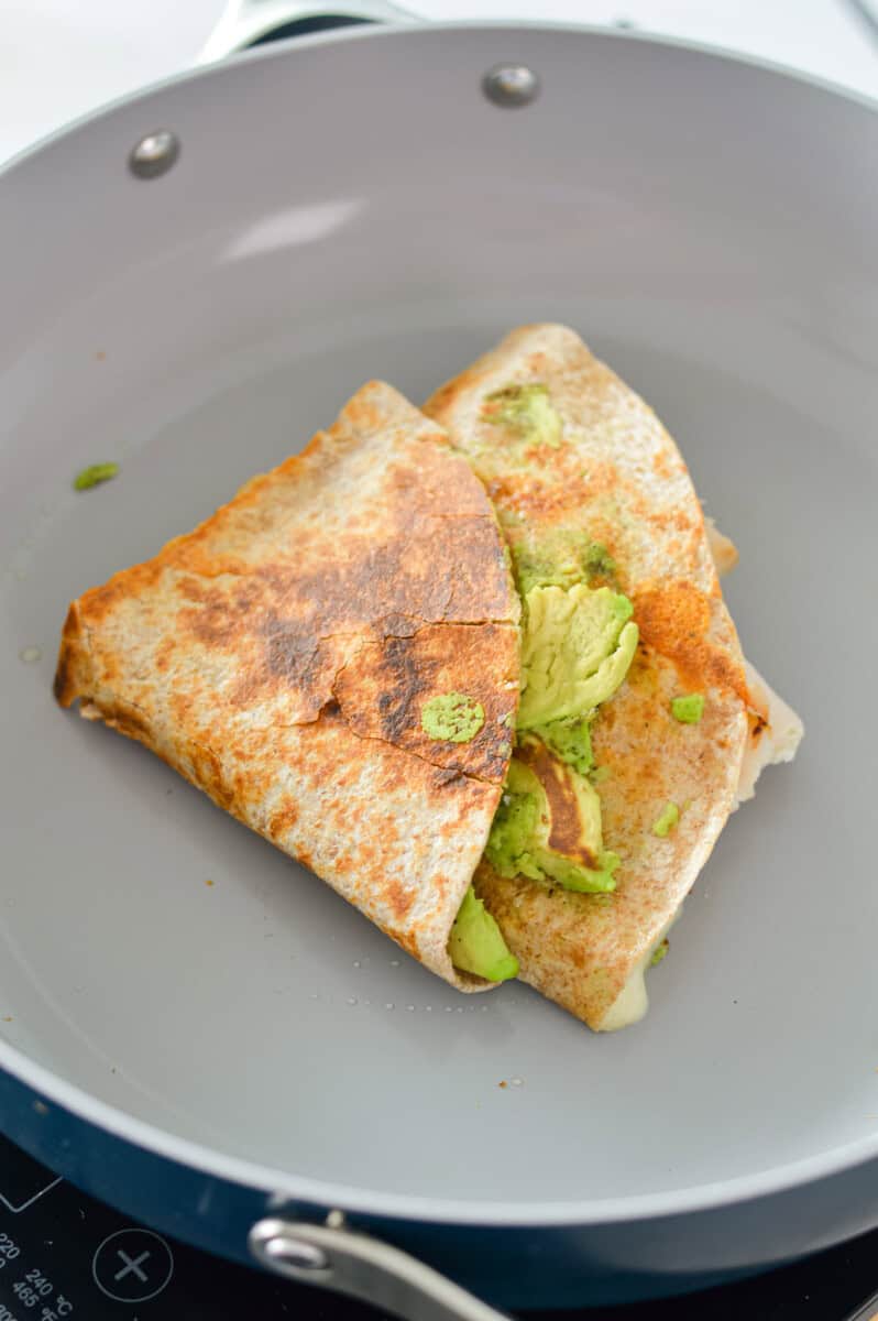 Cooking a turkey apple cheddar quesadilla on a pan.
