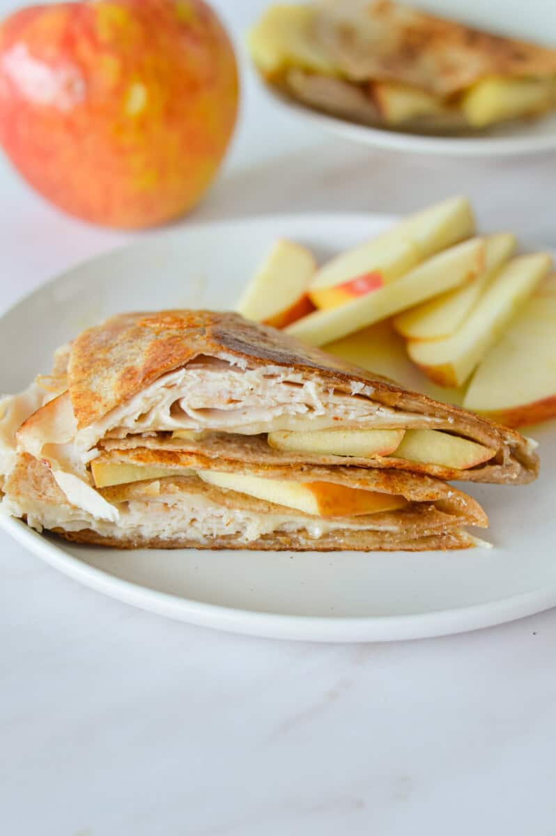 Lunch plate with turkey apple cheddar quesadilla and sliced apples.