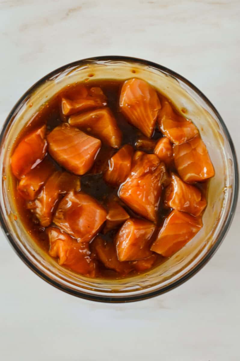 Marinating cubed salmon in teriyaki sauce.