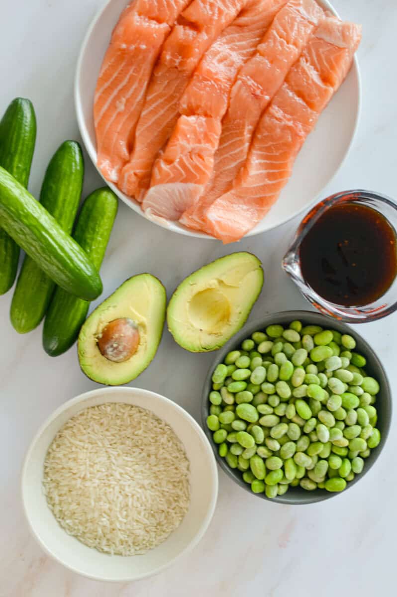 Ingredients including salmon fillets, cucumber, avocado, edamame, teriyaki sauce and rice.