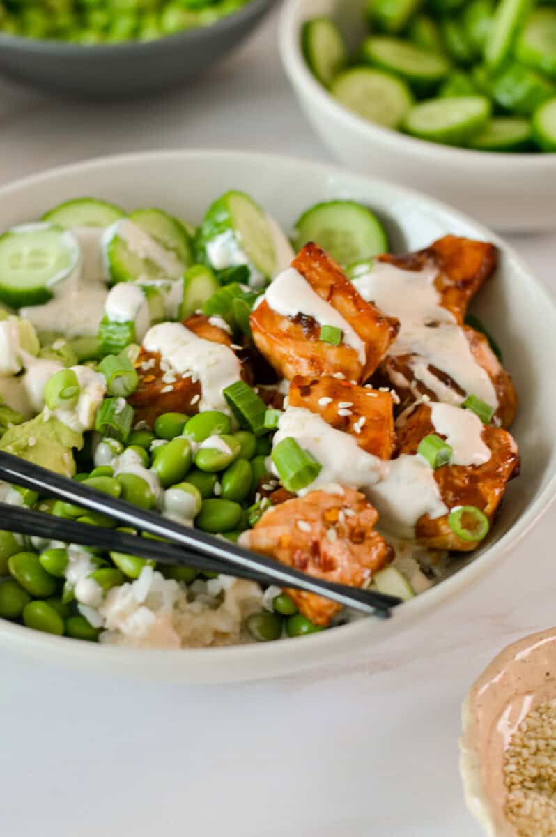 Close up of teriyaki salmon bowls with sriracha mayo drizzled on top.