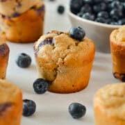 Table with blueberry cottage cheese muffins with blueberries scattered between.