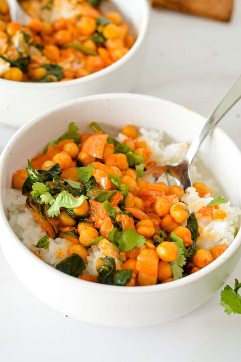 Bowl with chickpea and spinach curry served on rice.
