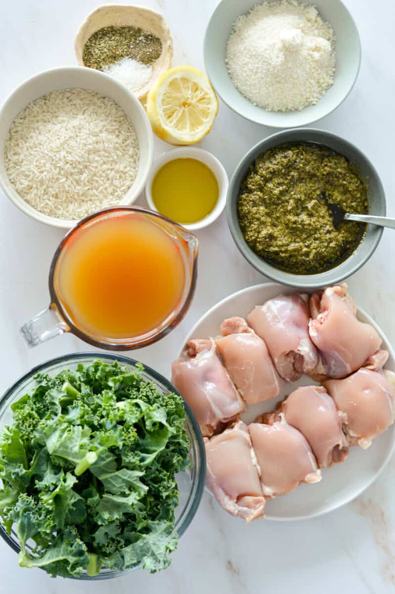 Ingredients including chicken thighs, kale, pesto, chicken broth, rice, olive oil, Parmesan, lemon, and spices.