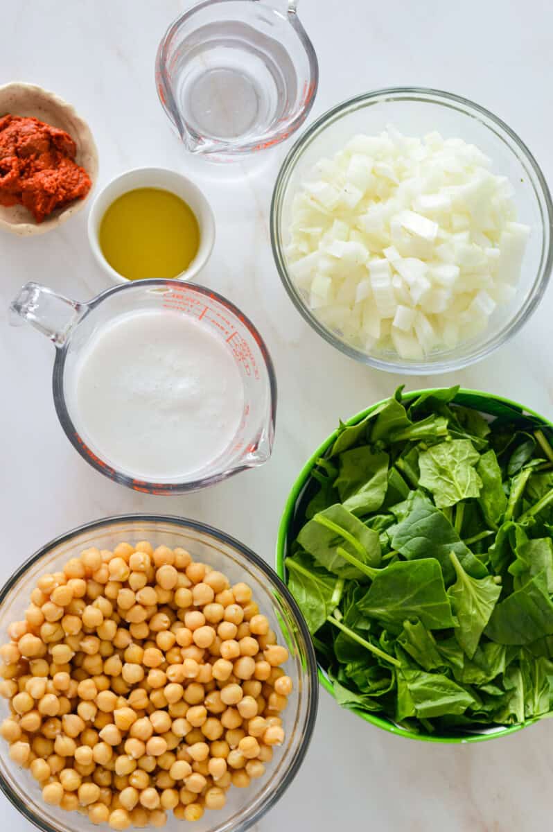 Ingredients including chickpeas, spinach, onions, coconut milk, oil and red curry paste.