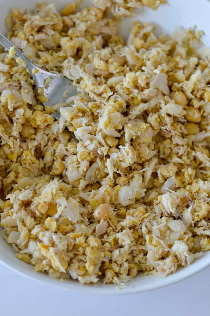 Mashing chickpeas and tuna with a fork.