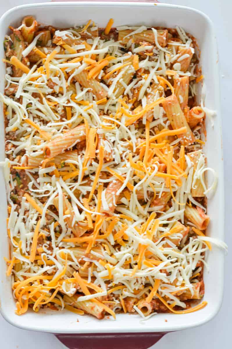 Adding pasta to casserole dish and topping with cheese.