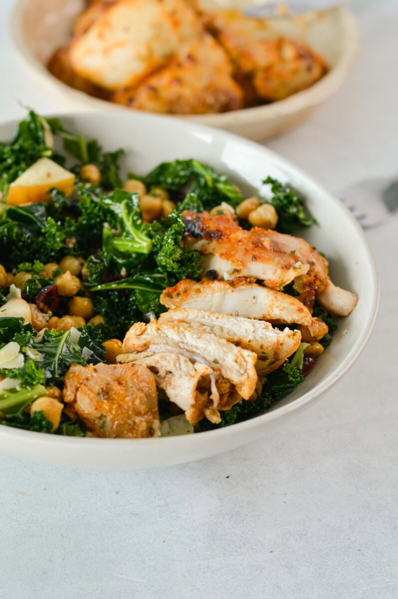 Bowl of salad served with sliced chicken thigh.