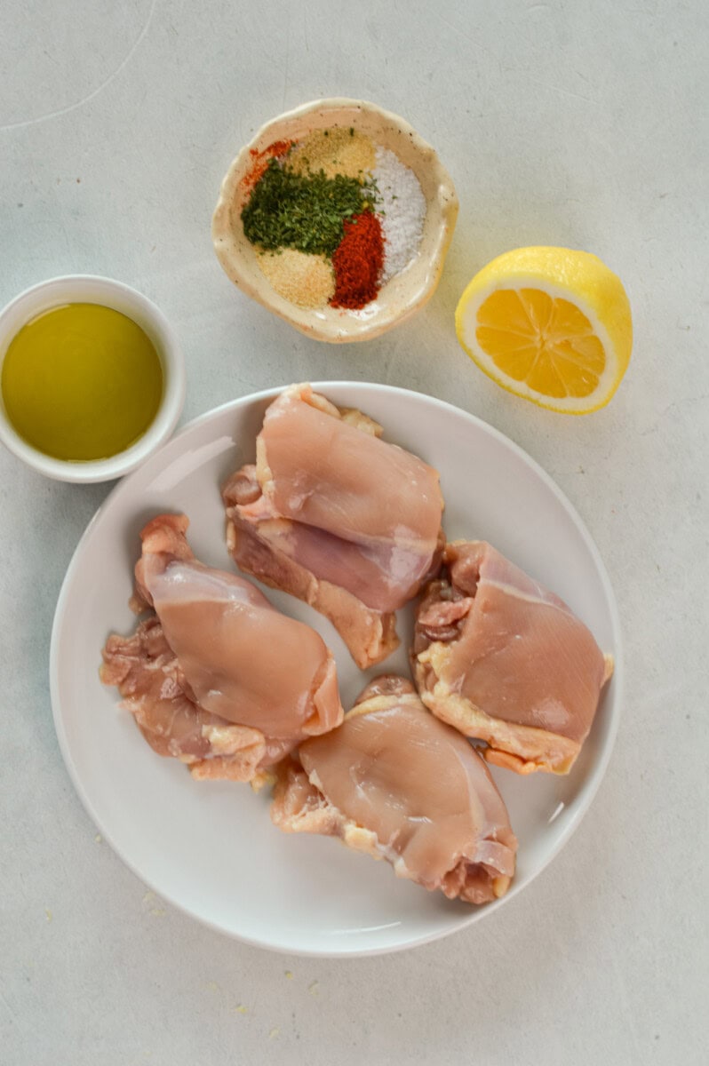 Ingredients including chicken thigh, lemon, olive oil and seasoning.