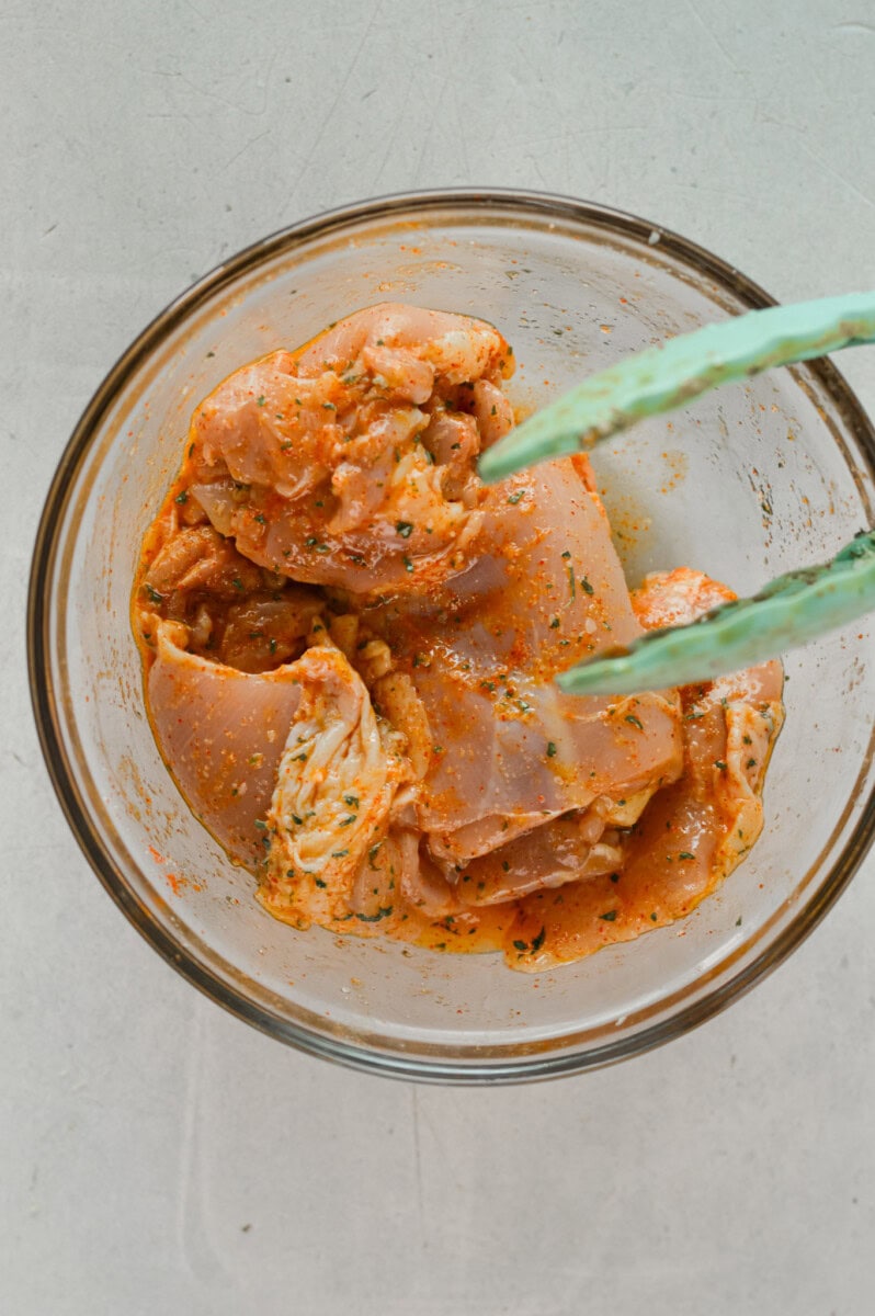 Marinating chicken thighs in olive oil, lemon juice and spices.