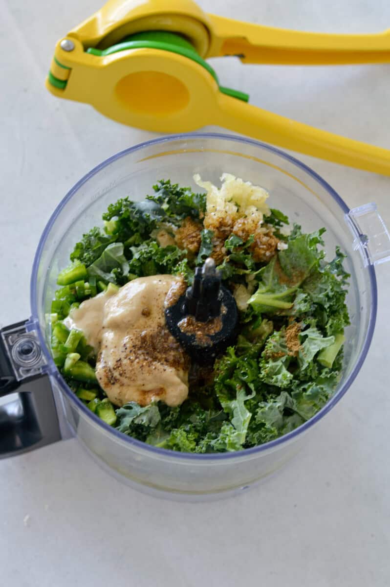 Adding all ingredients for edamame dip to a food processor.