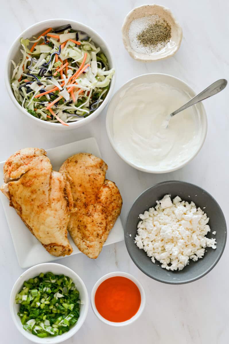 Ingredients including chicken, buffalo sauce, mayonnaise, greek yogurt, feta, coleslaw and green onion.