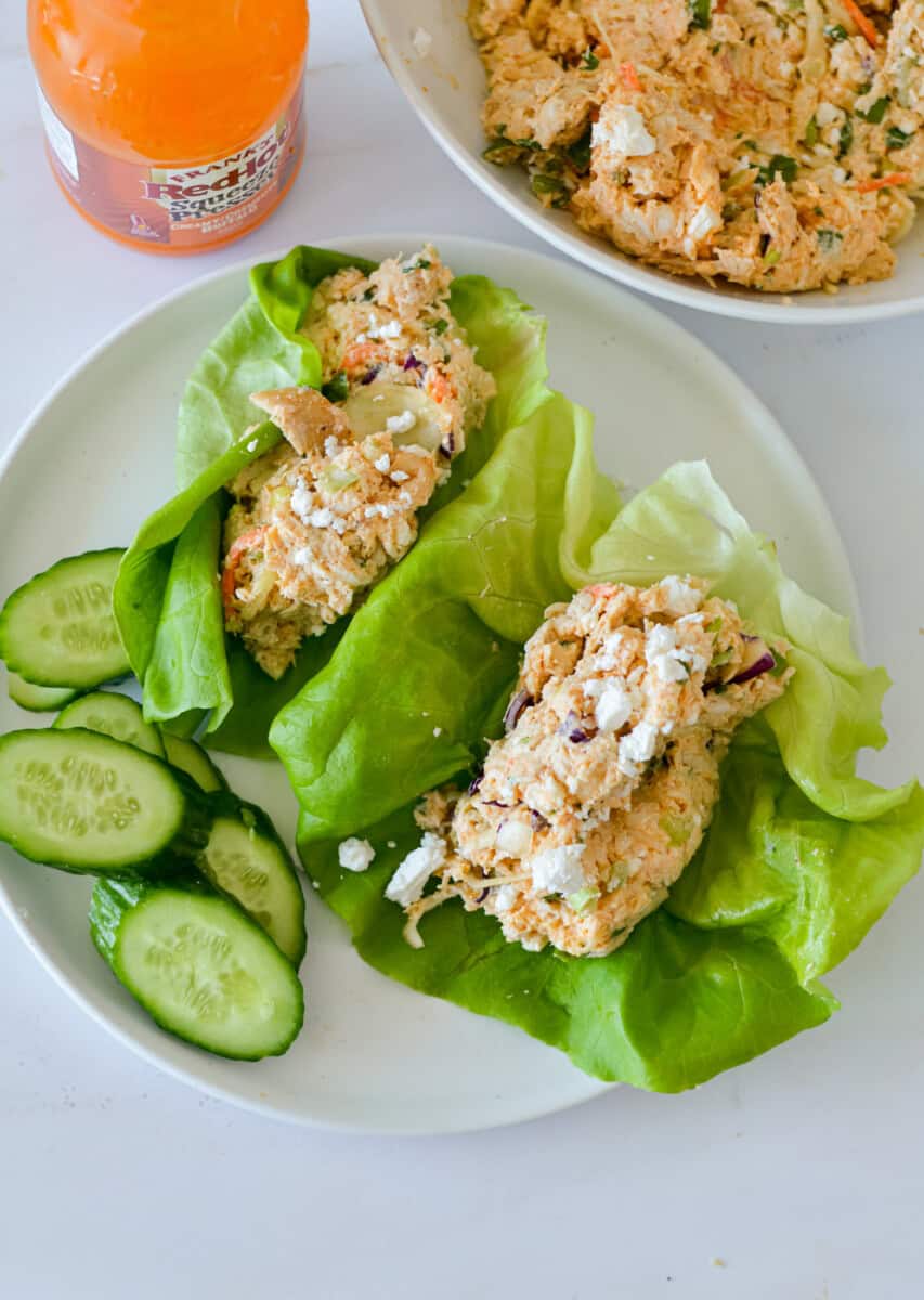 Birds eye of a plate with buffalo chicken lettuce wraps and cucumber slices.