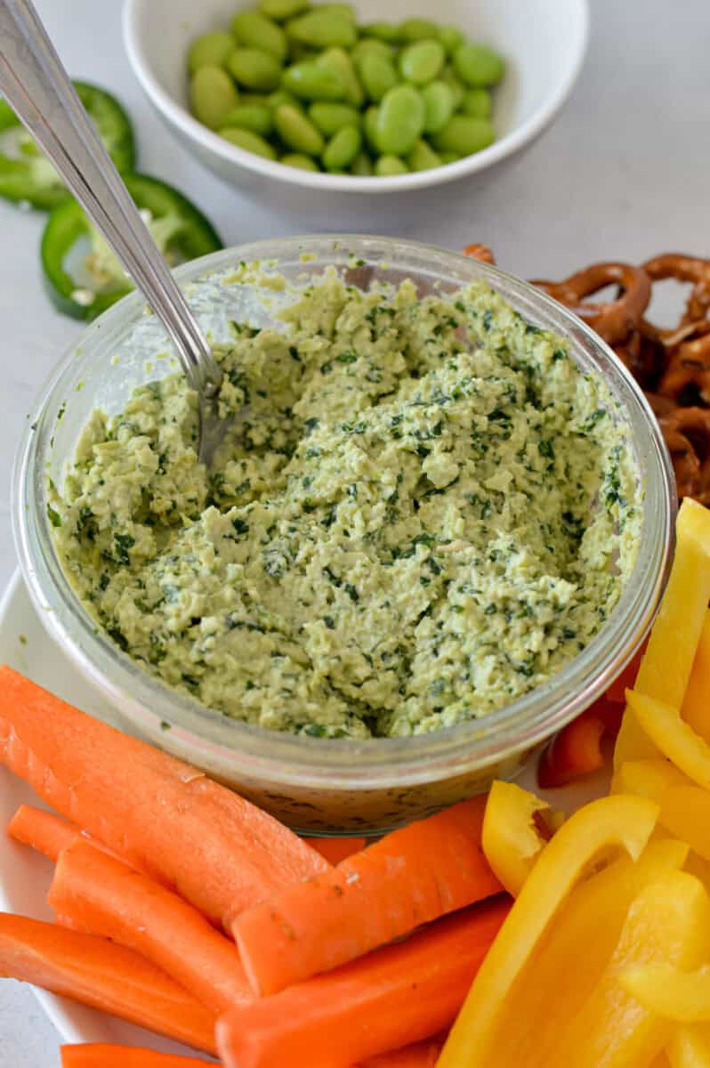 Close up of edamame dip, on a plate of veggies.