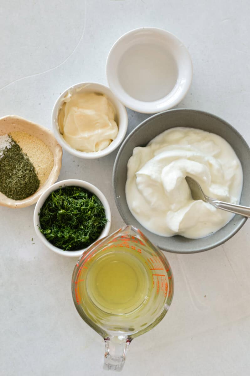 Birds eye of ingredients including greek yogurt, mayonnaise, spices, dill and pickle juice.