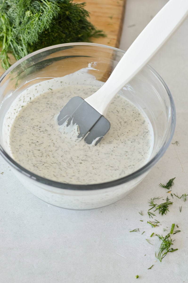 Mixing together dill pickle pasta salad dressing.