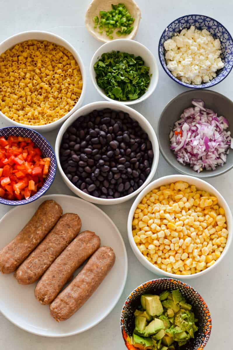 Ingredients including cotija cheese, black beans, chicken sausage, avocado, beans, red onion, red pepper and corn.