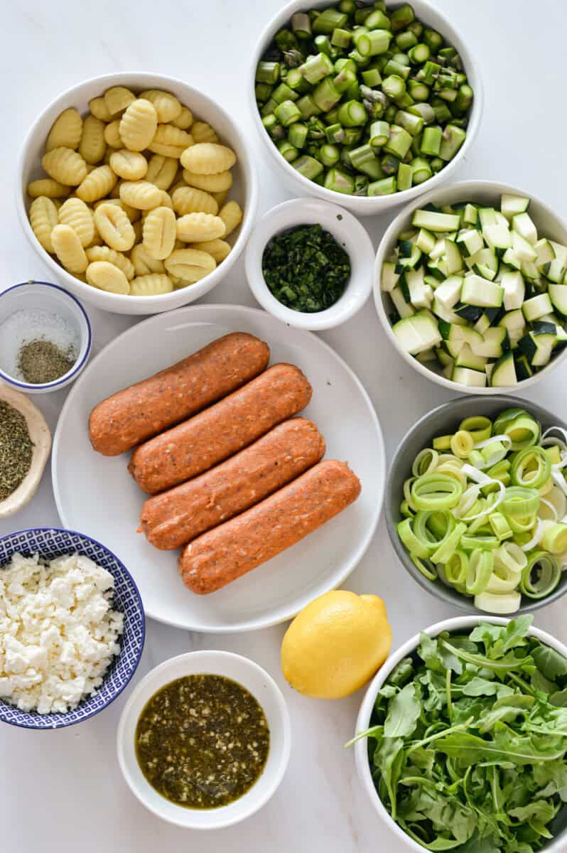 Birds eye of ingredients including sausage, zucchini, herbs, feta cheese, lemon, green onion, gnocchi and spices.