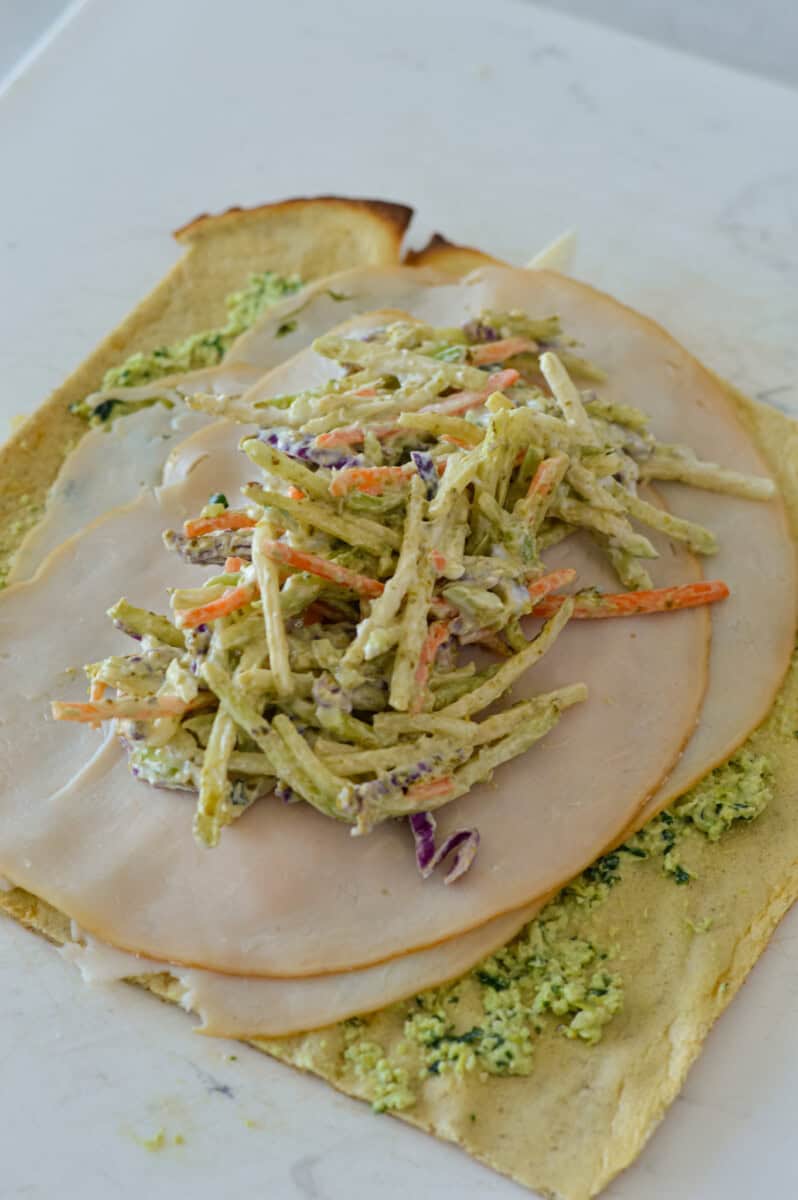 Making a wrap with cottage cheese wraps and pesto chicken filling.