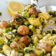 Close up of gnocchi, sausage and asparagus on a baking tray.