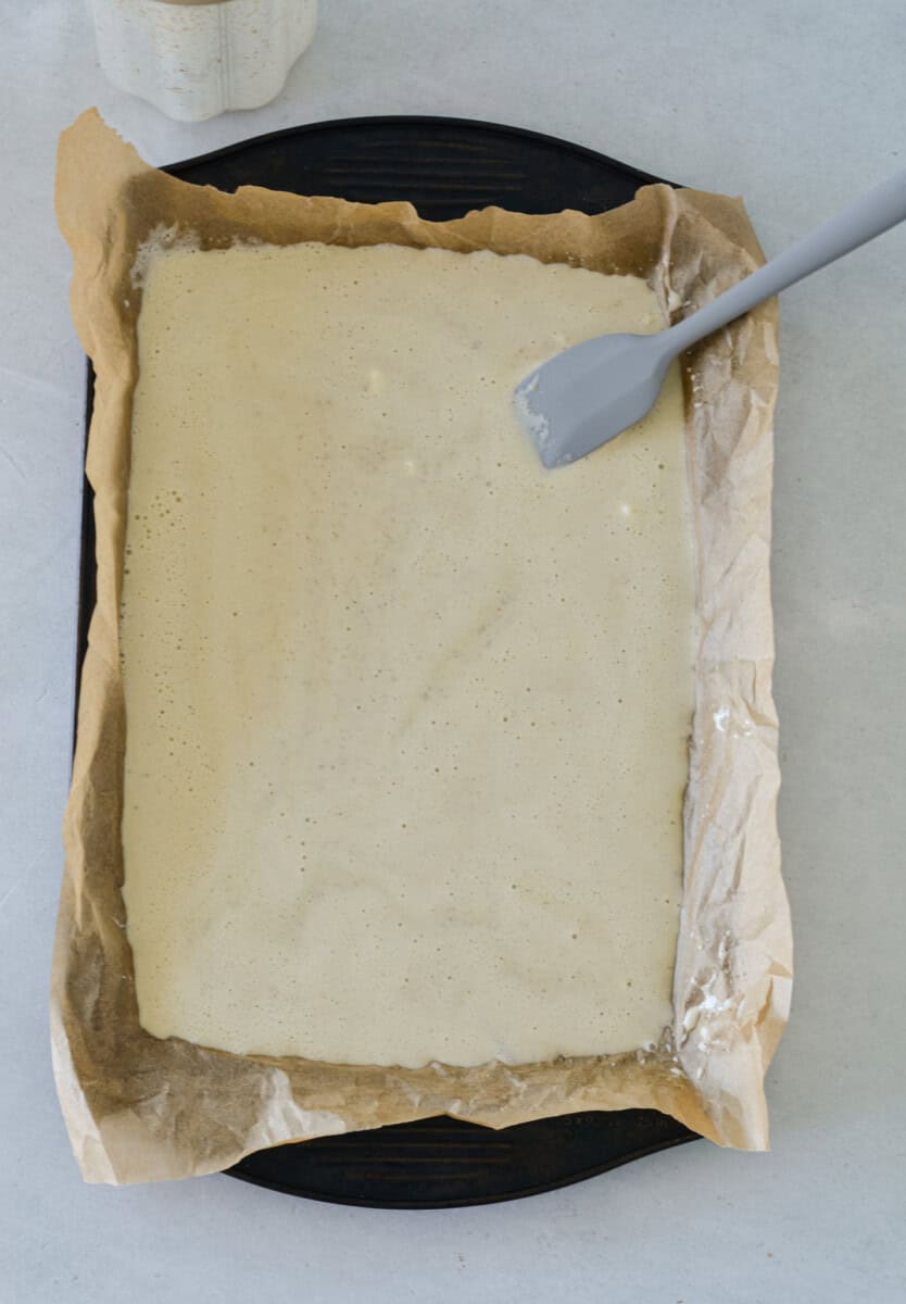 Spreading cottage cheese batter in a lined baking tray.