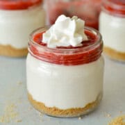 Close up of a strawberry cheesecake cup with whipped cream.