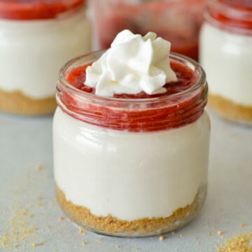 Close up of a strawberry cheesecake cup with whipped cream.