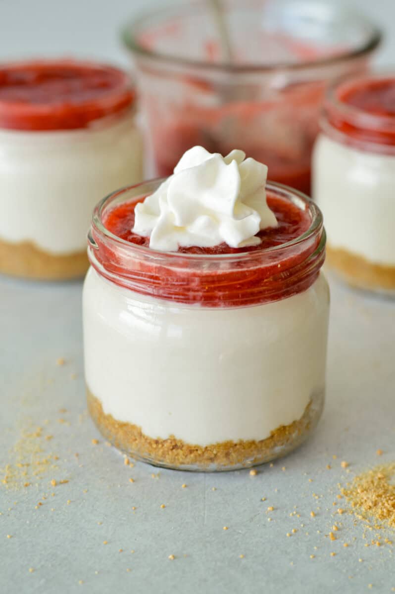 Close up of a strawberry cheesecake cup with whipped cream.
