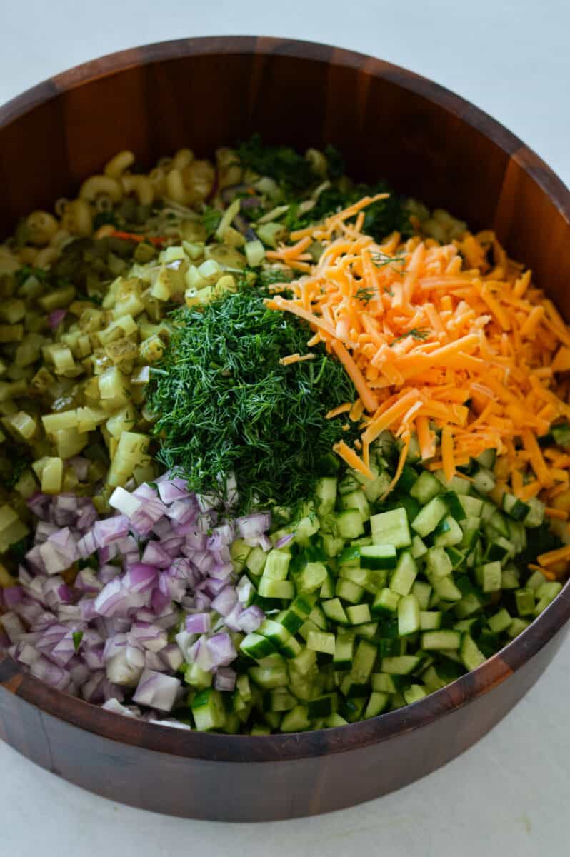 To a large bowl add- cooked pasta, chickpeas, kale slaw, cucumbers, pickles, red onion, dill and cheese. 