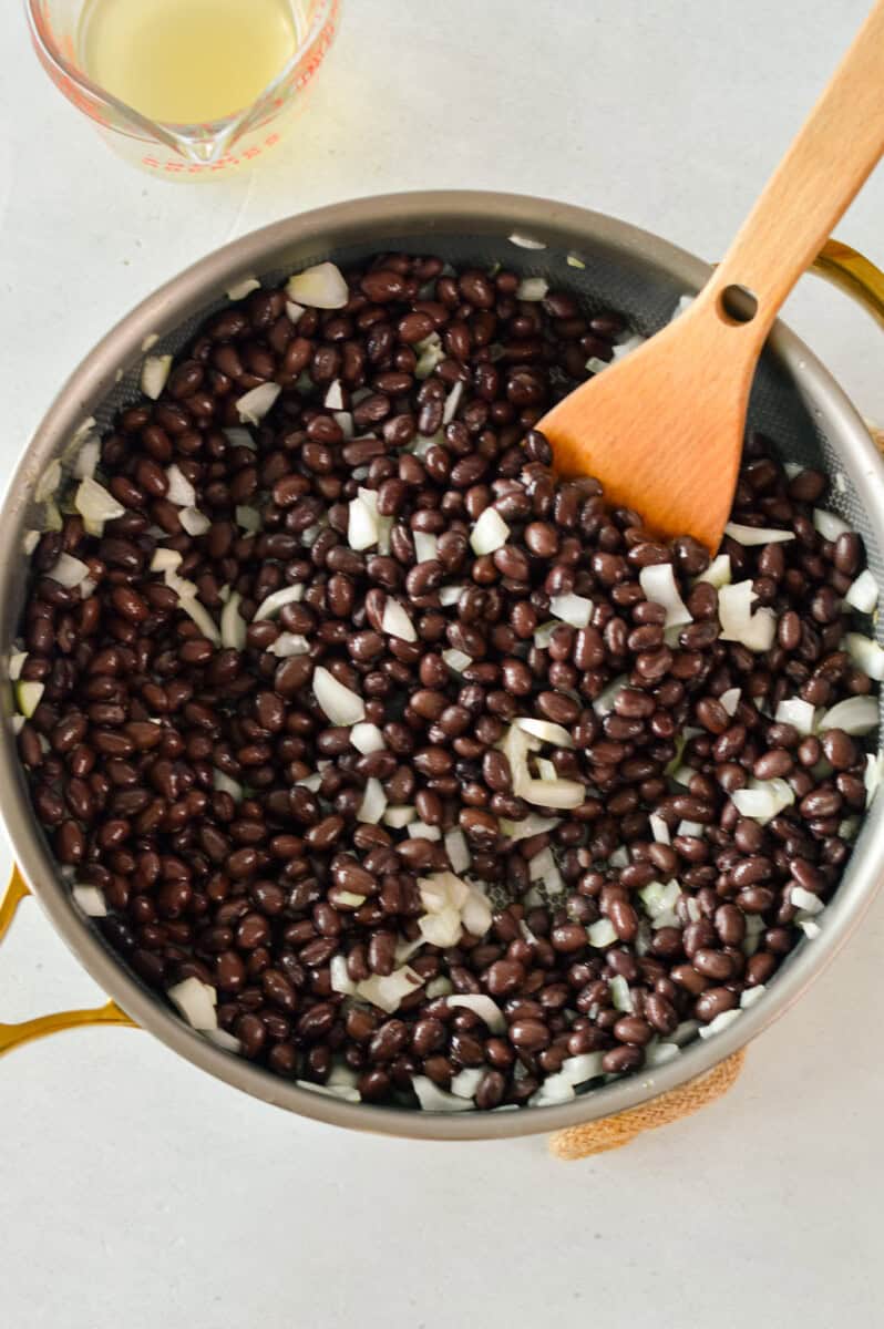 Mixing a pot of black beans and onions.