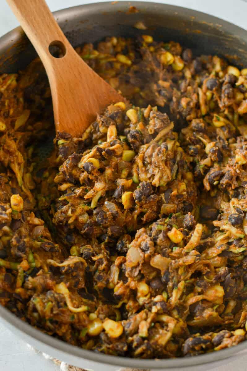 Stirring taco seasoning and nutritional yeast into black bean taco mixture.