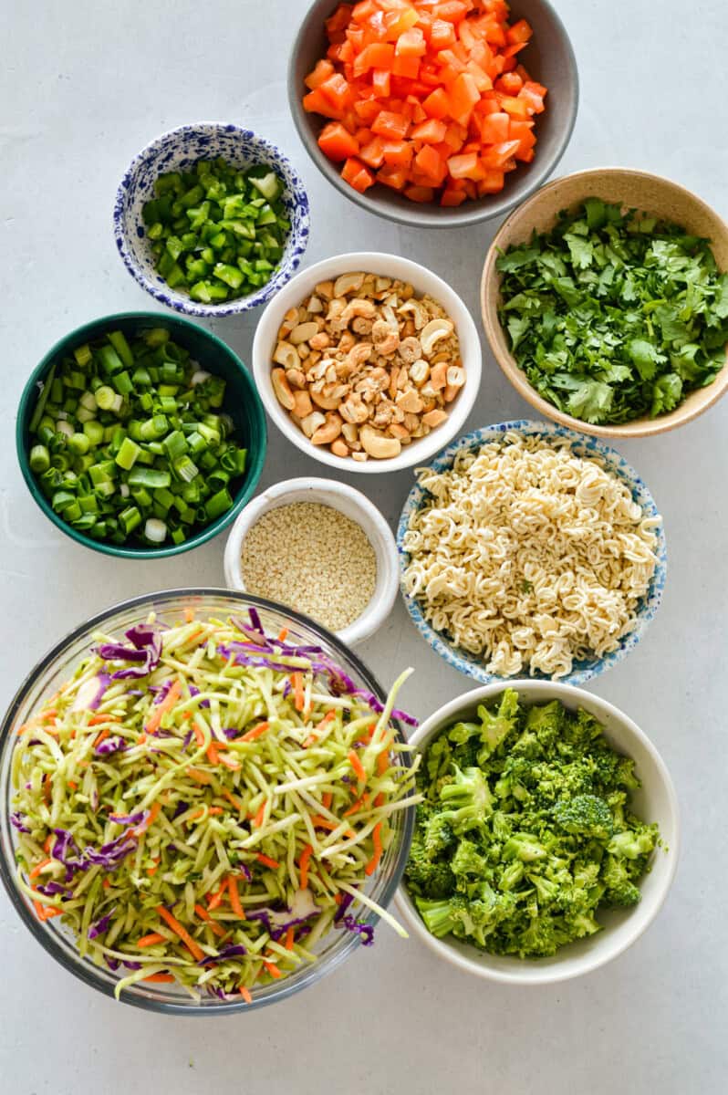 Birds eye of ingredients including ramen noodles, cilantro, green onion, broccoli slaw, sesame, cashews, bell pepper and broccoli.
